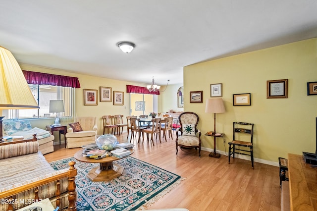 living room with baseboards, light wood-style floors, and a chandelier