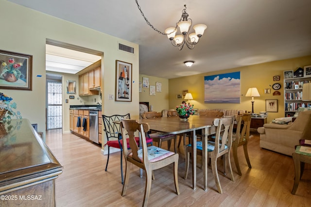 dining area featuring visible vents, a chandelier, and light wood-style flooring