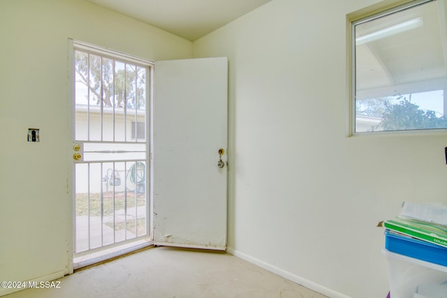 unfurnished room with baseboards and concrete flooring