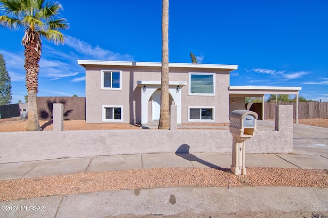 view of front of house with an attached carport, stucco siding, and fence