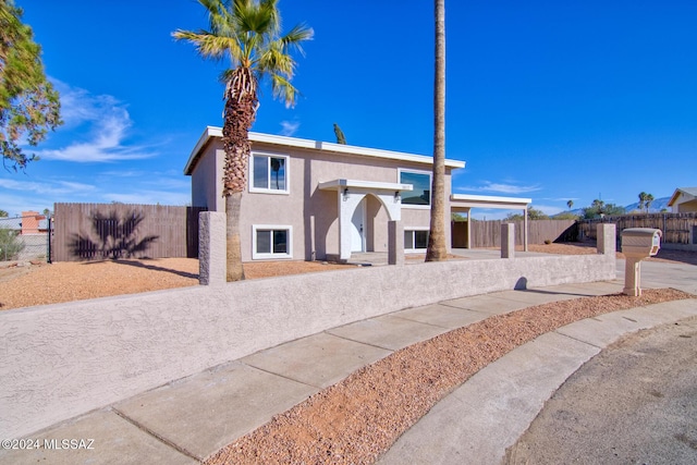 view of front facade with stucco siding and fence
