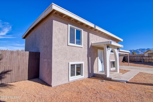back of house with a mountain view, stucco siding, and fence