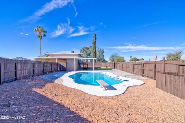 view of pool featuring a patio, a fenced in pool, a fenced backyard, and a diving board