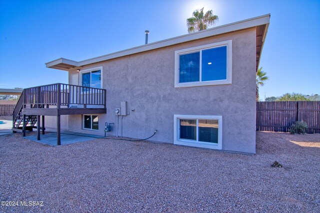 back of house featuring stucco siding, stairs, fence, and a patio area