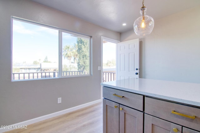 kitchen featuring baseboards, light stone countertops, recessed lighting, decorative light fixtures, and light wood-type flooring