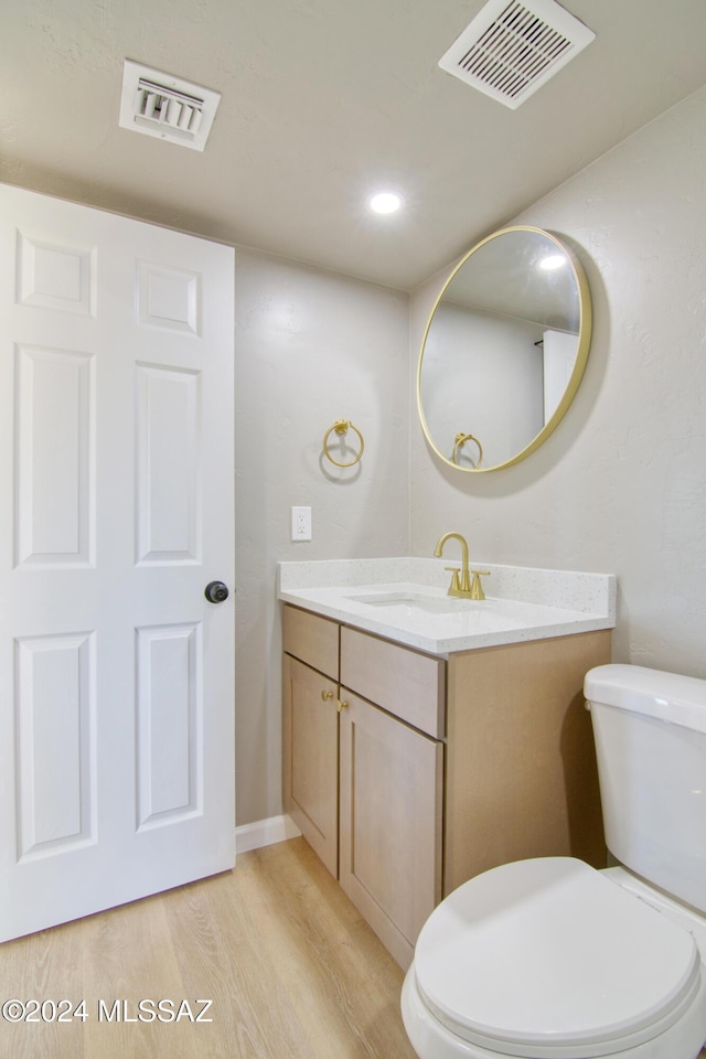 bathroom with toilet, visible vents, wood finished floors, and vanity