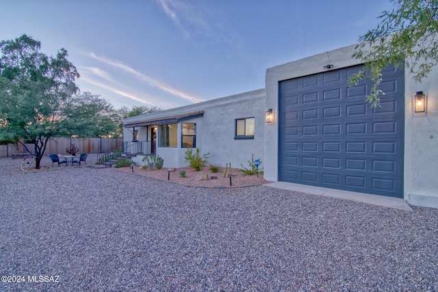 view of front of house featuring a garage, stucco siding, and fence