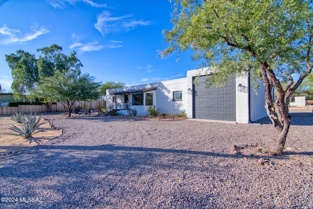 single story home featuring a garage, fence, and stucco siding