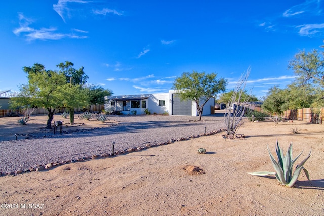 view of front facade with gravel driveway, fence, and an attached garage