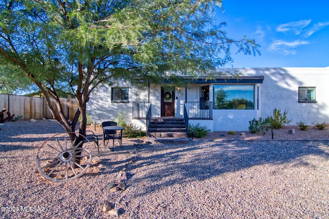 view of front of home featuring stucco siding and fence