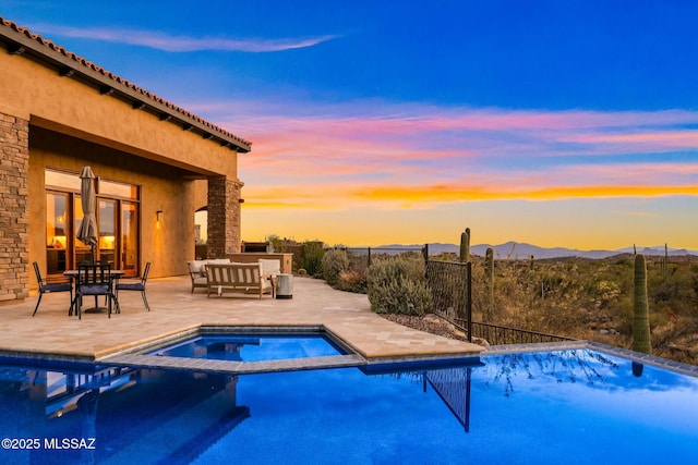 14623 N Shaded Stone Pl, Oro Valley, AZ 85755 - pool at dusk with a pool with connected hot tub, a mountain view, fence, and a patio