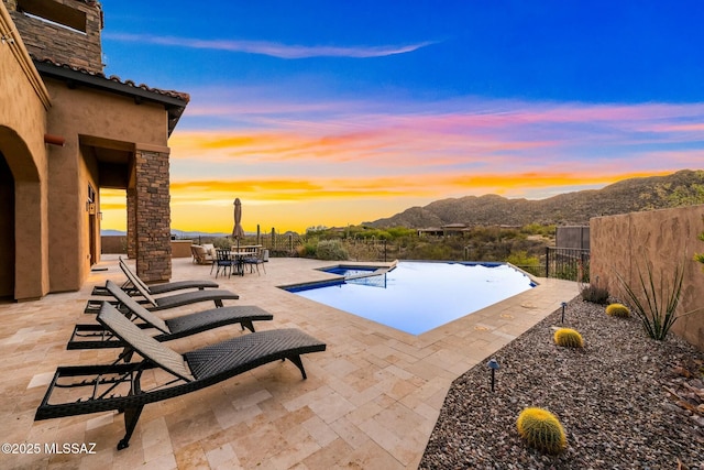 14623 N Shaded Stone Pl, Oro Valley, AZ 85755 - pool at dusk featuring a fenced backyard, a patio, outdoor dining space, a mountain view, and a fenced in pool