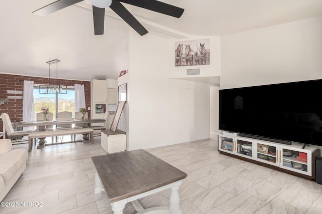 living area featuring high vaulted ceiling, ceiling fan, visible vents, and brick wall