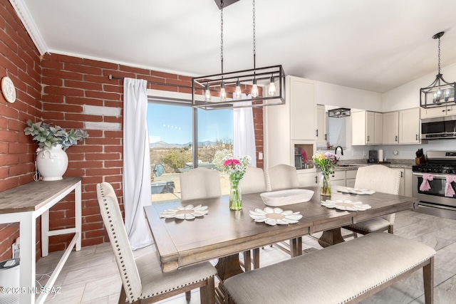 dining space featuring an inviting chandelier and brick wall