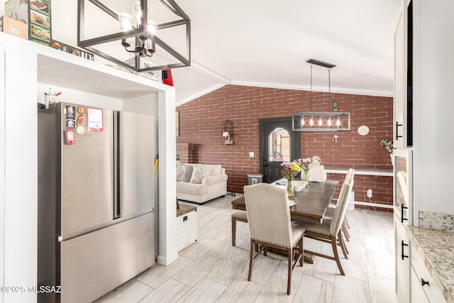 dining area with an inviting chandelier, brick wall, and lofted ceiling