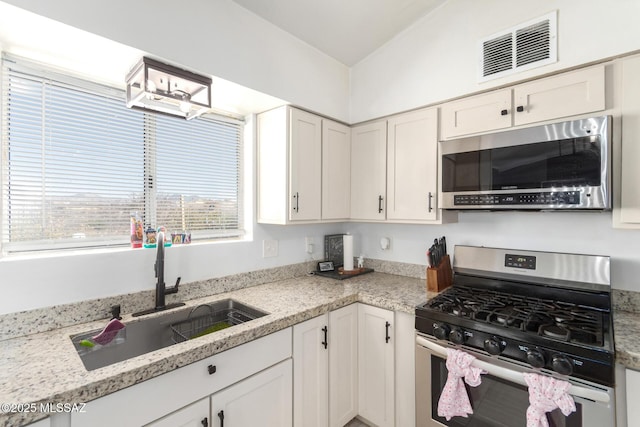 kitchen featuring visible vents, white cabinets, a sink, and stainless steel appliances