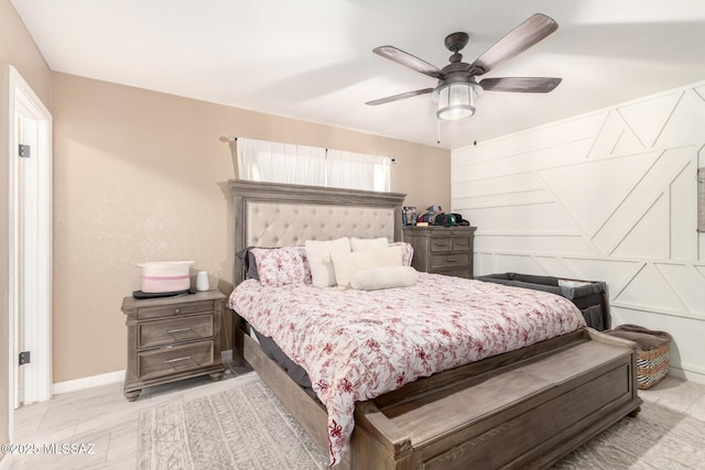 bedroom with a ceiling fan, a decorative wall, and baseboards