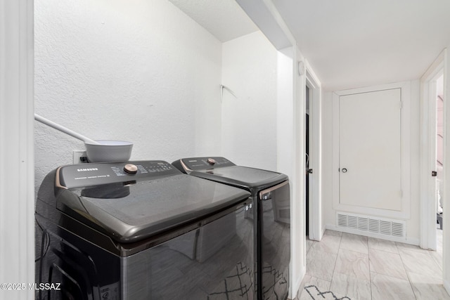 clothes washing area featuring a textured wall, marble finish floor, visible vents, washing machine and dryer, and laundry area