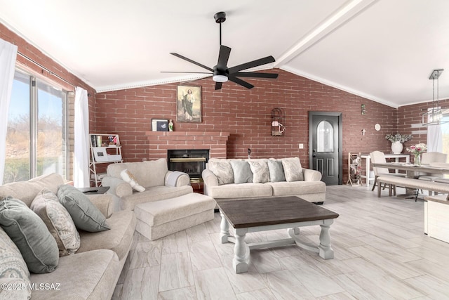 living area featuring lofted ceiling with beams, a fireplace, brick wall, ceiling fan, and ornamental molding