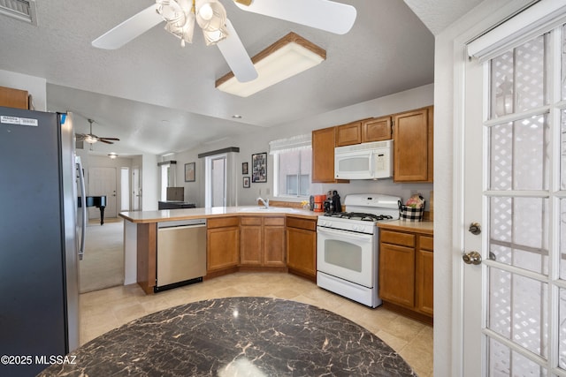 4654 W Gatehinge Ct, Tucson, AZ 85741 - kitchen featuring appliances with stainless steel finishes, a ceiling fan, a sink, a peninsula, and brown cabinetry