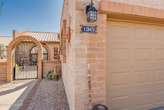 doorway to property featuring a tile roof, a gate, and brick siding