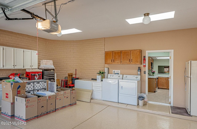 garage featuring washing machine and clothes dryer, a garage door opener, and freestanding refrigerator