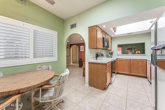 kitchen with electric stove, light tile patterned flooring, arched walkways, visible vents, and black microwave