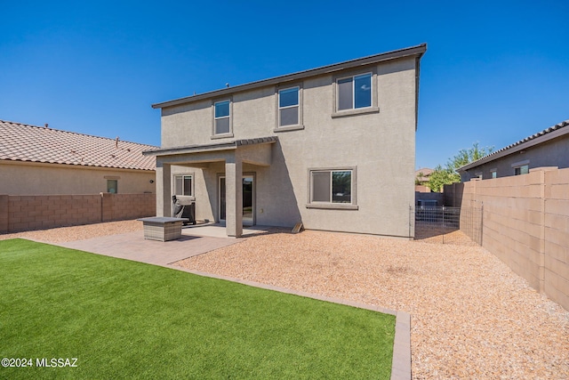 rear view of property with a fenced backyard, a lawn, stucco siding, and a patio area