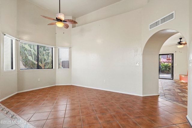 spare room featuring arched walkways, ceiling fan, visible vents, and tile patterned flooring