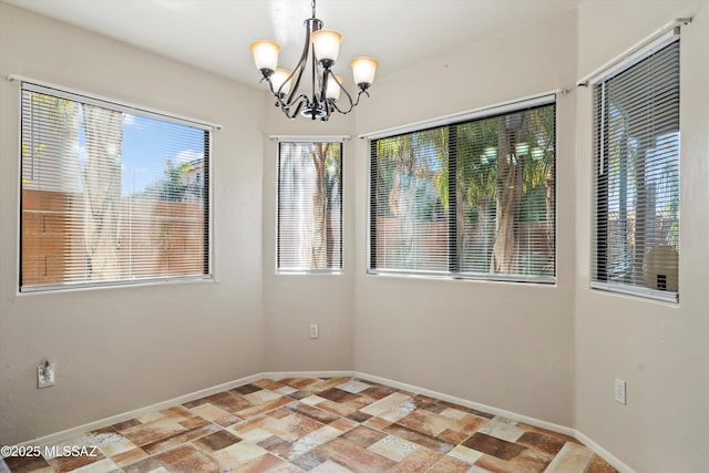 empty room with baseboards and a chandelier