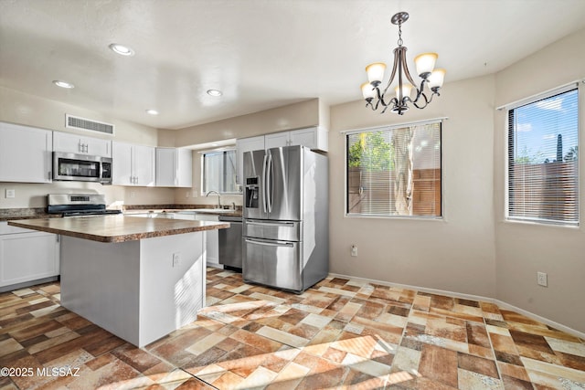 kitchen with a center island, a sink, visible vents, white cabinets, and appliances with stainless steel finishes