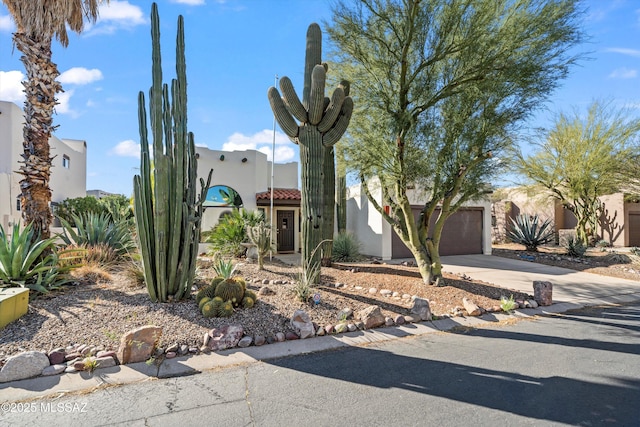 southwest-style home with a tile roof, driveway, and stucco siding