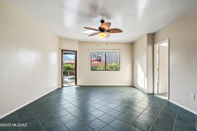 unfurnished room featuring a ceiling fan, dark tile patterned floors, and baseboards