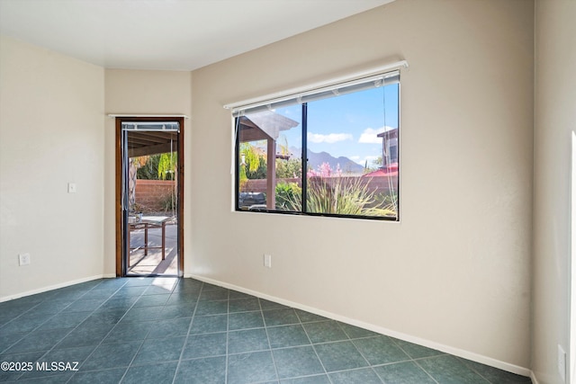 spare room featuring baseboards and dark tile patterned flooring