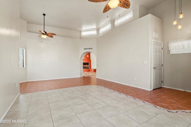 empty room with visible vents, arched walkways, light tile patterned floors, and a ceiling fan