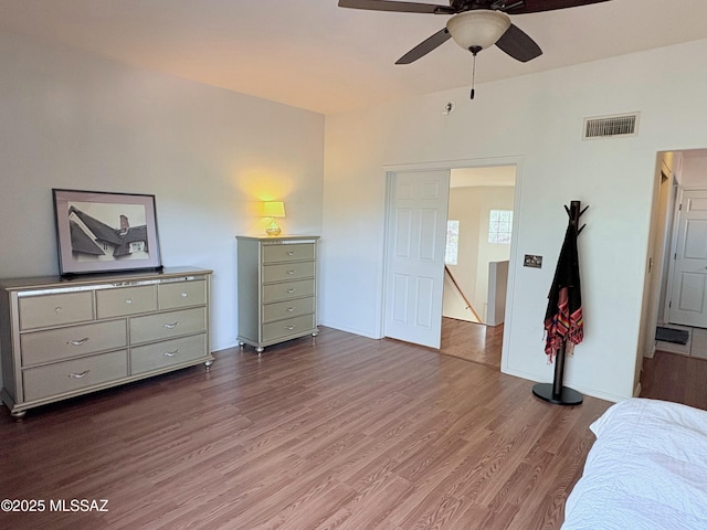 bedroom with ceiling fan, visible vents, baseboards, and wood finished floors