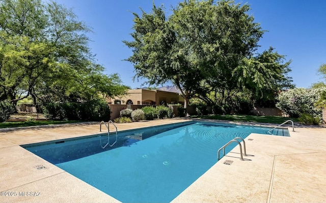 outdoor pool with a patio area and fence