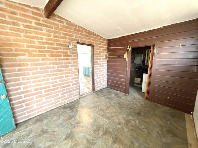 empty room with vaulted ceiling with beams, wood walls, brick wall, and concrete flooring