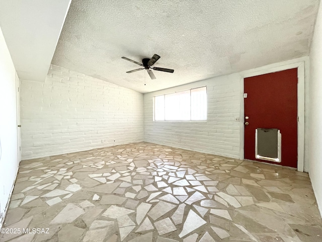 spare room featuring a textured ceiling, stone flooring, ceiling fan, lofted ceiling, and heating unit