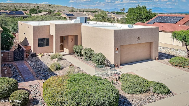 pueblo-style house featuring stucco siding, a garage, and concrete driveway