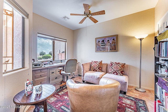 living area with baseboards, a wealth of natural light, visible vents, and a ceiling fan