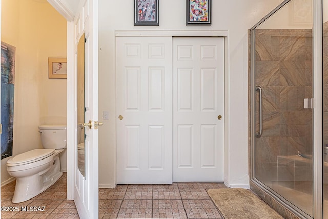 bathroom featuring a stall shower, baseboards, toilet, and tile patterned flooring