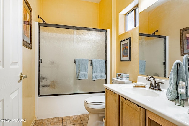 bathroom with toilet, bath / shower combo with glass door, and vanity