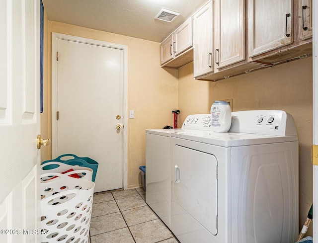 washroom with light tile patterned floors, cabinet space, washing machine and dryer, and visible vents