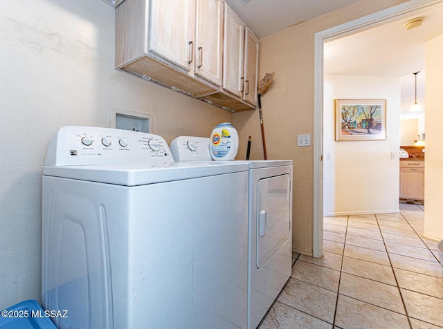 clothes washing area with cabinet space, washing machine and dryer, and light tile patterned floors