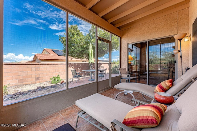 sunroom featuring beamed ceiling and outdoor dining space