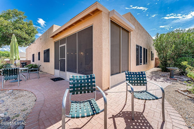 view of patio with outdoor dining space and a sunroom