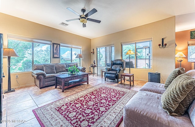 tiled living area featuring plenty of natural light, baseboards, visible vents, and a ceiling fan