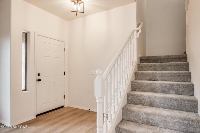 entryway with stairs, baseboards, and wood finished floors