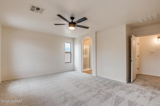unfurnished bedroom featuring carpet, arched walkways, and visible vents